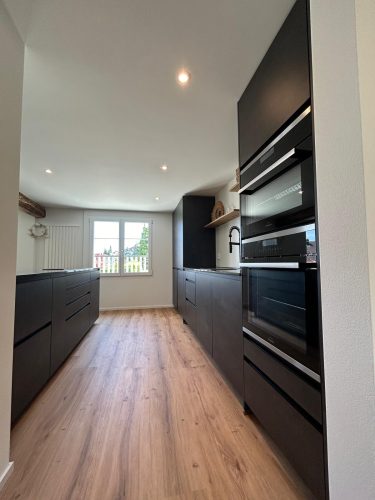 Moderne schwarze Einbauküche mit hochwertigen Geräten.