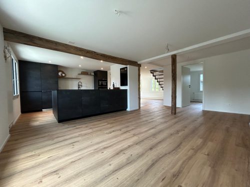 Offener Wohnbereich mit moderner schwarzer Küche und Echtholzfussboden